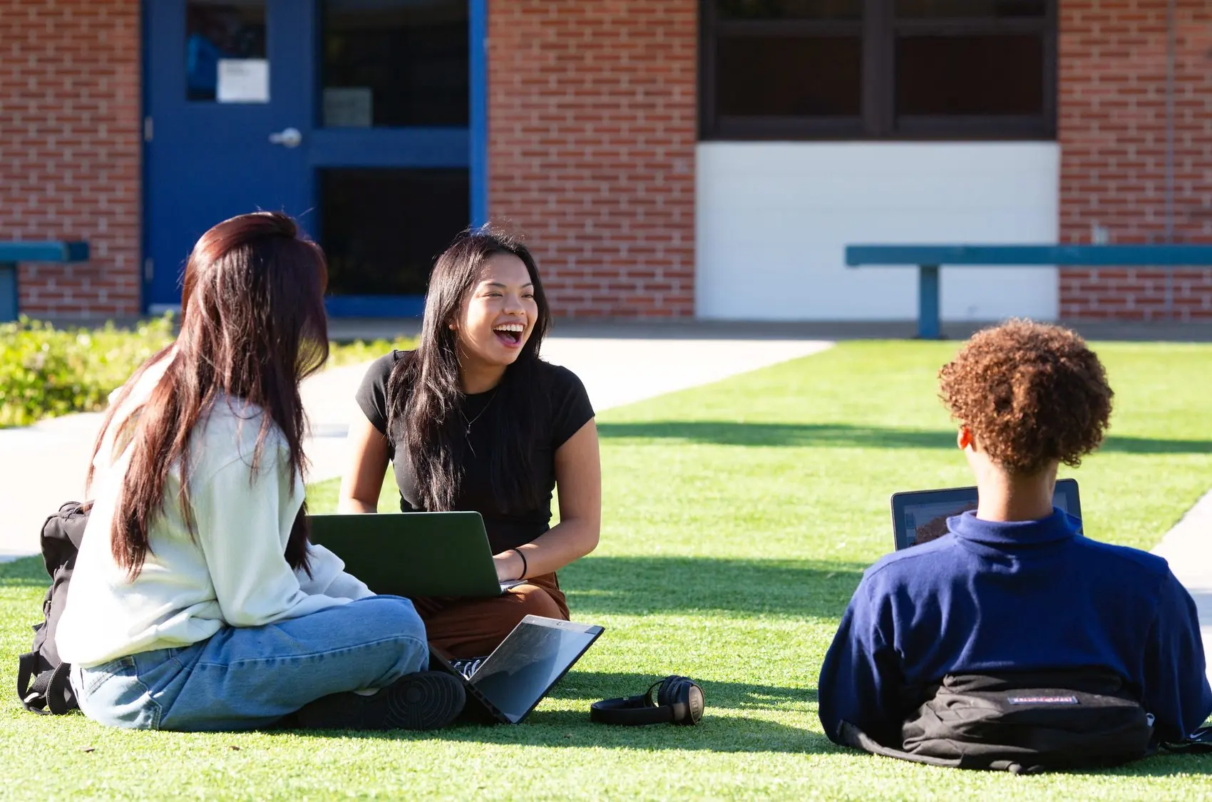 Students sitting together on the lawn outside the school.
